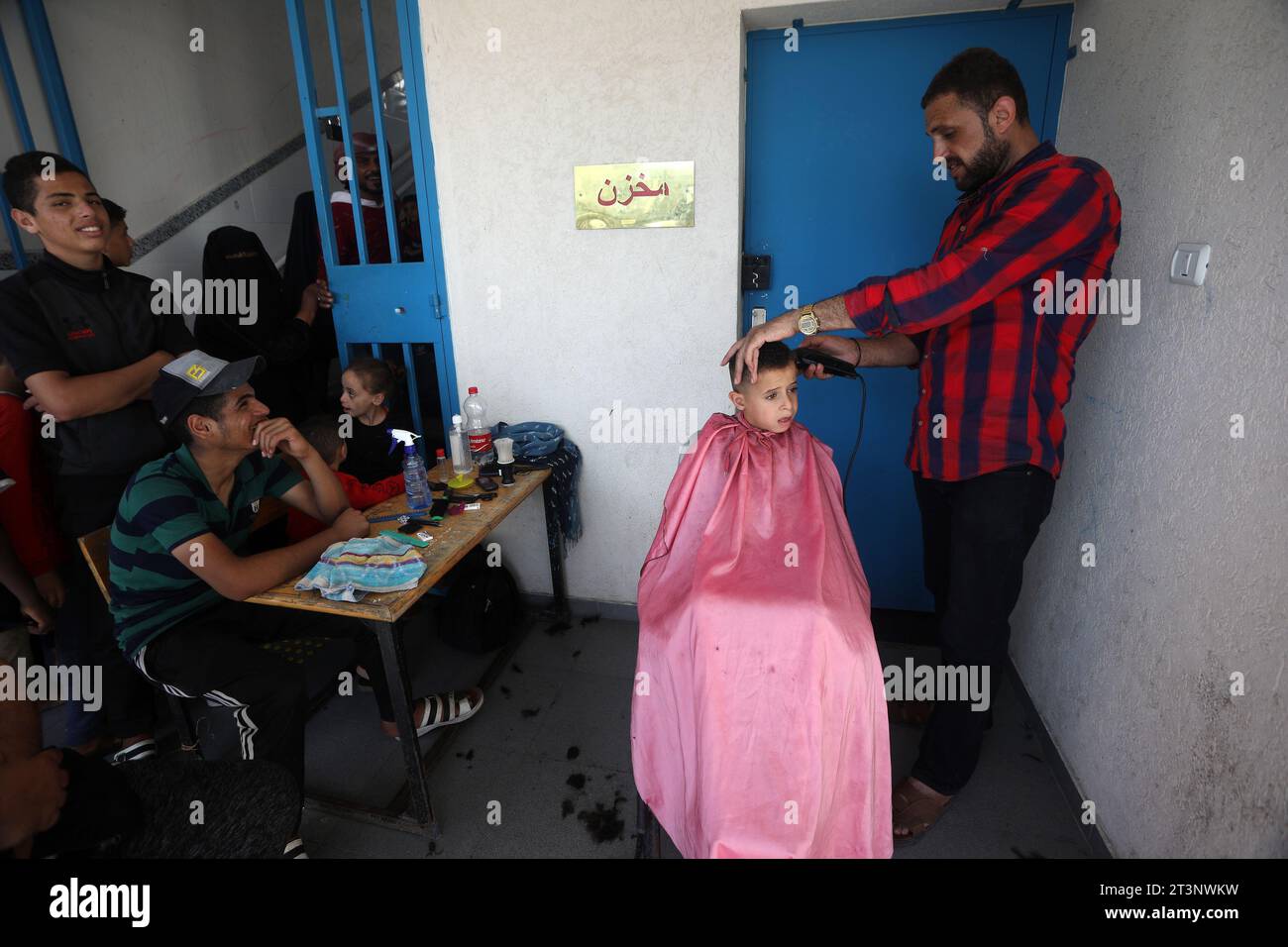 Rafah, Gaza. Oktober 2023. Ein Friseur schneidet einem Kind die Haare auf der Flucht mit seinen Familien israelische Angriffe suchen Zuflucht in einer Schule, die dem Hilfswerk der Vereinten Nationen für Palästinaflüchtlinge im Nahen Osten (UNRWA) in Rafah im südlichen Gaza-Streifen am 20. Oktober 2023 angehört. Die israelischen Luftangriffe werden am 20. Tag in Gaza fortgesetzt. Foto: Ismael Mohamad/UPI Credit: UPI/Alamy Live News Stockfoto