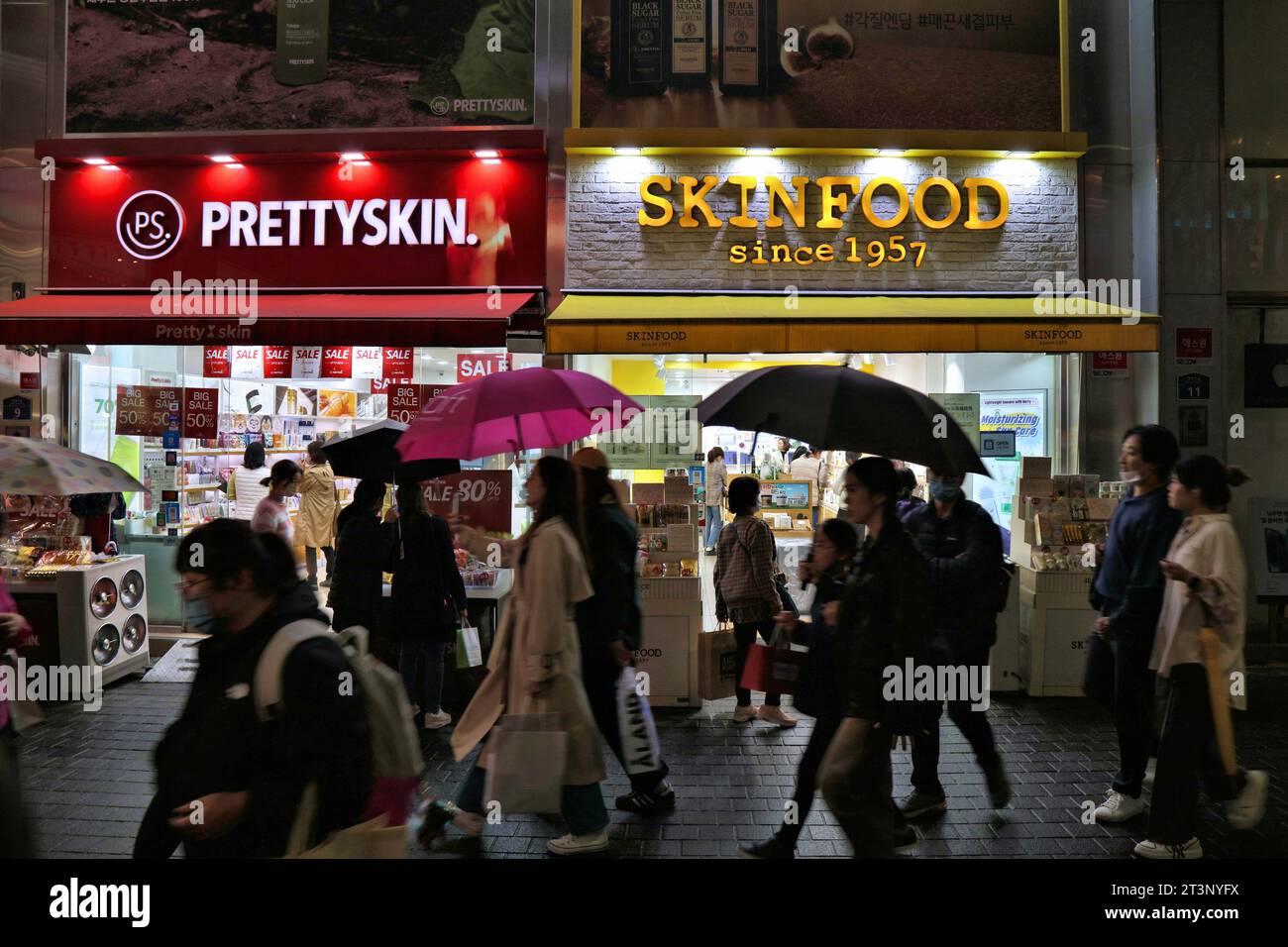 SEOUL, SÜDKOREA - 5. APRIL 2023: Besucher besuchen Prettyskin und Skinfood Korean Beauty Stores im Einkaufsviertel Myeongdong in Seoul bei Nacht. Stockfoto