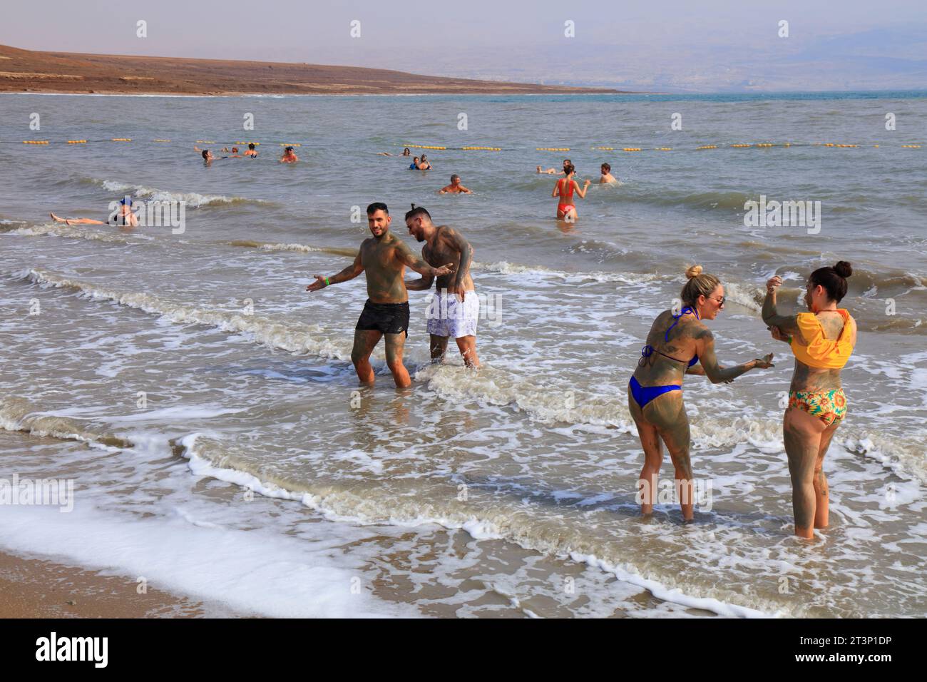 TOTES MEER, ISRAEL - 30. OKTOBER 2022: Touristen besuchen den Strand am Toten Meer in Israel. Das Tote Meer ist der tiefste Punkt der Erde, mit dem berühmten dunklen Schlamm, der man glaubt Stockfoto