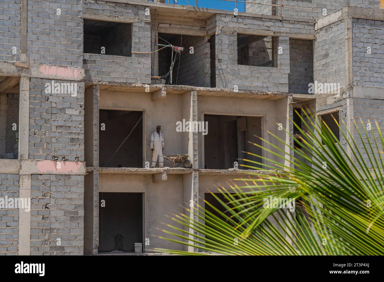 Santa Maria, Sal Island - Kap Verde, 02.10.2023: Bau eines unvollendeten Gebäudes mit einem Mann in weißer Arbeitskleidung Stockfoto