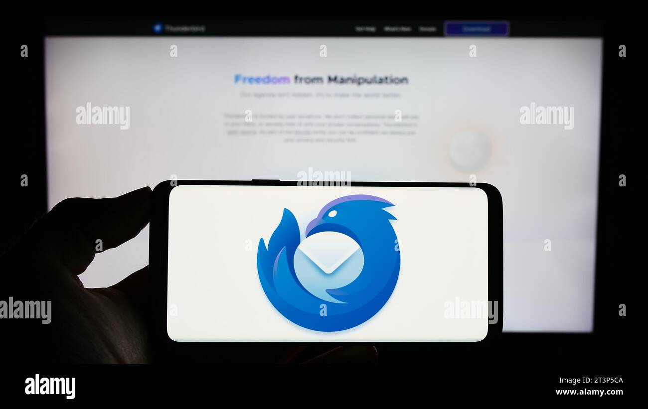 Person mit Smartphone und Logo des Open-Source-E-Mail-Clients Mozilla Thunderbird vor der Website. Schwerpunkt auf dem Display des Telefons. Stockfoto