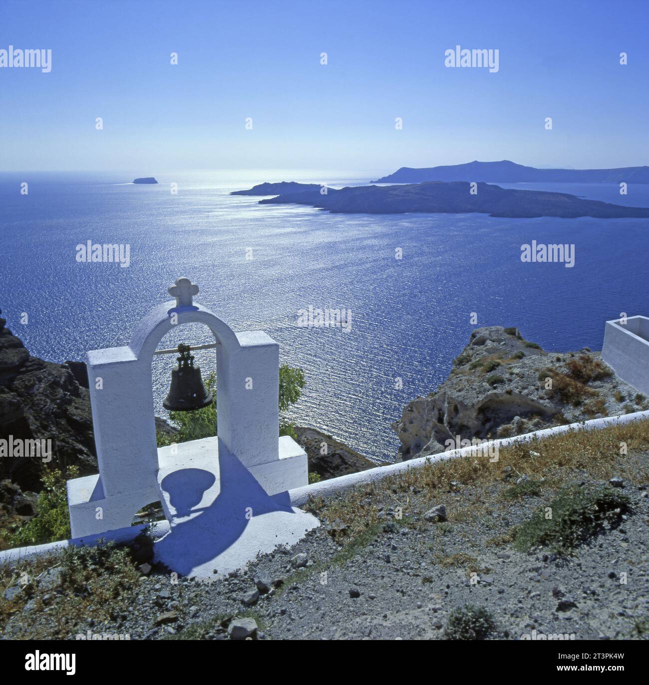 Santorin: Blick auf Aspronisi vom Kraterrand, im Vordergrund kleiner gemauerter Glockenstuhl*Glocke und überqueren Sie das Meer auf der sonnigen Thira Stockfoto