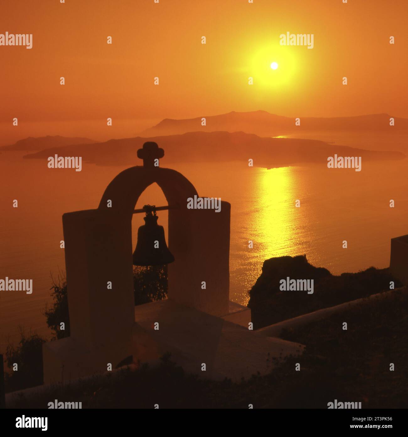 Santorin:Sonnenuntergang,Inseln Nea Kameni und Therasia, im Vordergrund:Glocke und Kreuz * Thira Sonnenuntergang mit Kreuz und Glocke Stockfoto