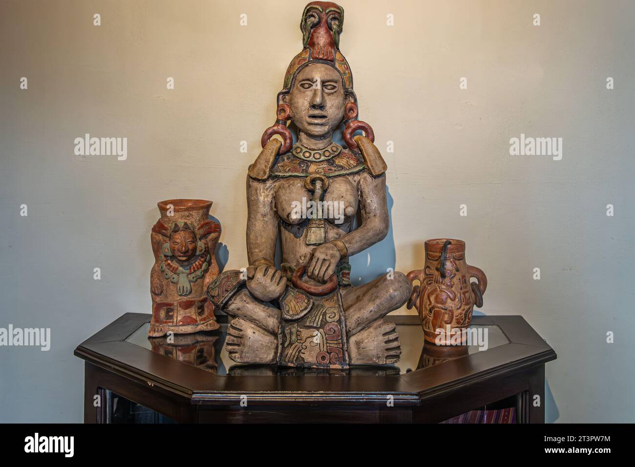 Guatemala, La Antigua - 20. Juli 2023: Jade Maya Museum. Nahaufnahme. Ixchel, Maya-Fruchtbarkeit und Mondgöttin-Statue auf dunklem Holzschrank, plus 2 kleine Stockfoto