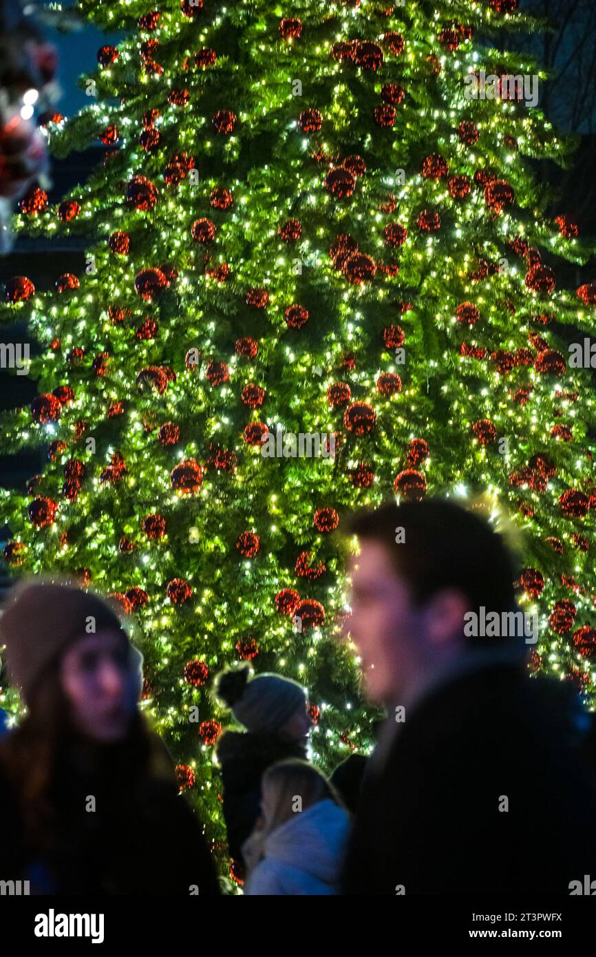 Leute stehen vor einem großen dekorierten weihnachtsbaum Stockfoto