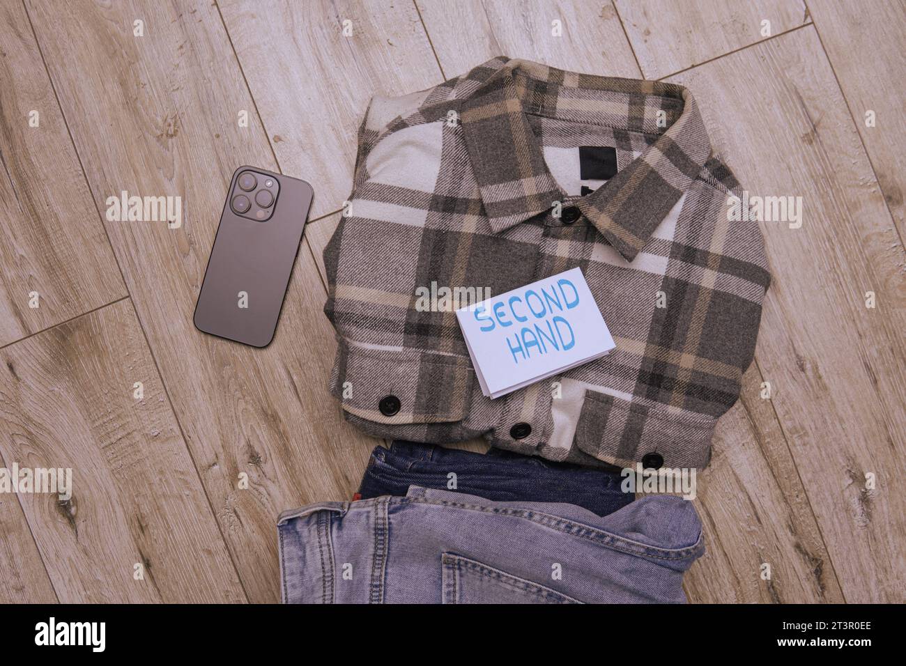 Flanellhemd und Jeans mit der Aufschrift Second Hand. Flachbild mit dem Verkauf von gebrauchter Kleidung Stockfoto