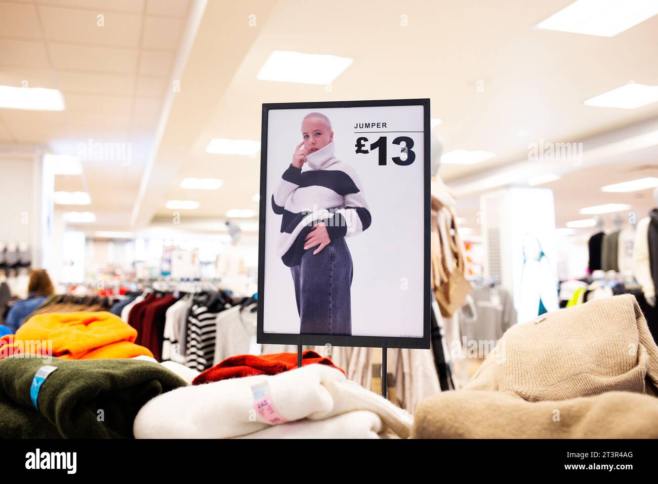 Schwarz-weiß gestreifter Pullover mit Polokragen im Wert von 13 £ auf einem Modell mit rasierendem weiblichem Kopf auf dem Werbeplakat im Primark Shop Torquay Stockfoto