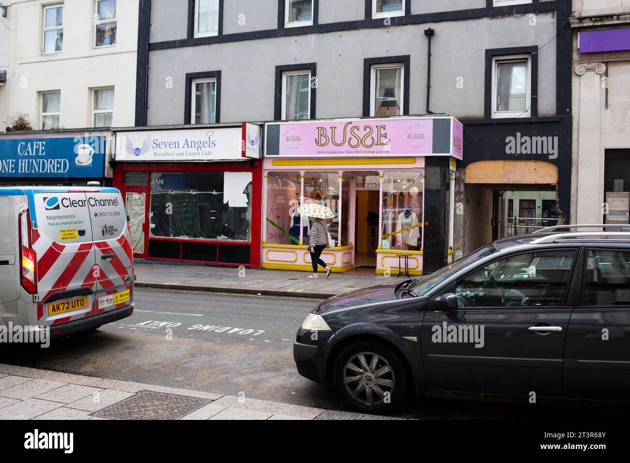 Union Street Torquay bei leichtem Regen und mit einer Dame, die einen Schirm auf der anderen Straßenseite hält Stockfoto