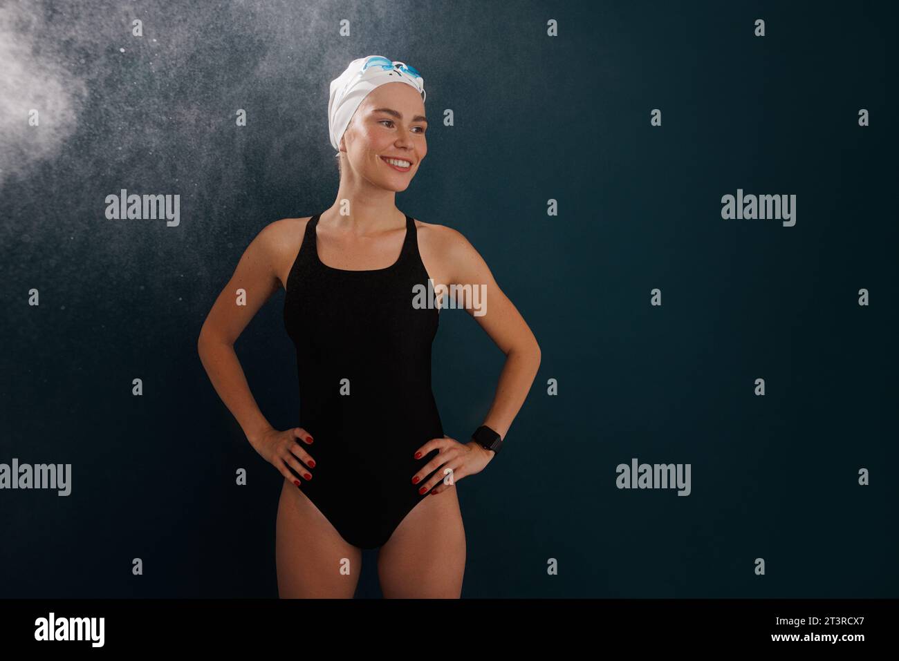 Gesunder, lächelnder professioneller Schwimmer unter dem Sprühnebel auf blauem Hintergrund Stockfoto