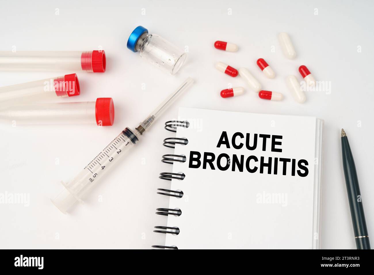 Medizinisches Konzept. Auf dem Tisch befinden sich Pillen, Injektionen, eine Spritze und ein Notizblock mit der Aufschrift - Akute Bronchitis Stockfoto