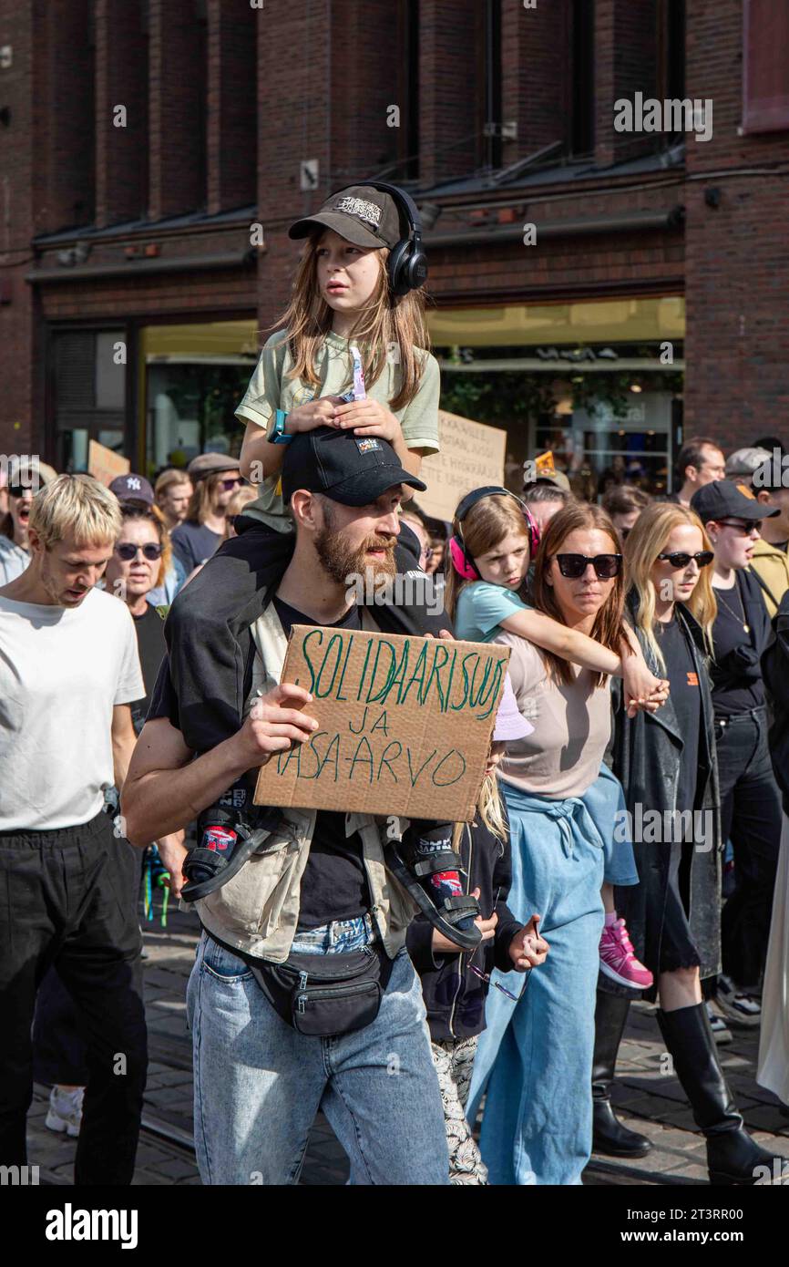 Solidaarisuus ja tasa-arvo. Mann mit einem Kind auf den Schultern, der ein Pappschild auf mich hält, emme vaikene! Anti-Rassismus-Demonstration in Helsinki. Stockfoto
