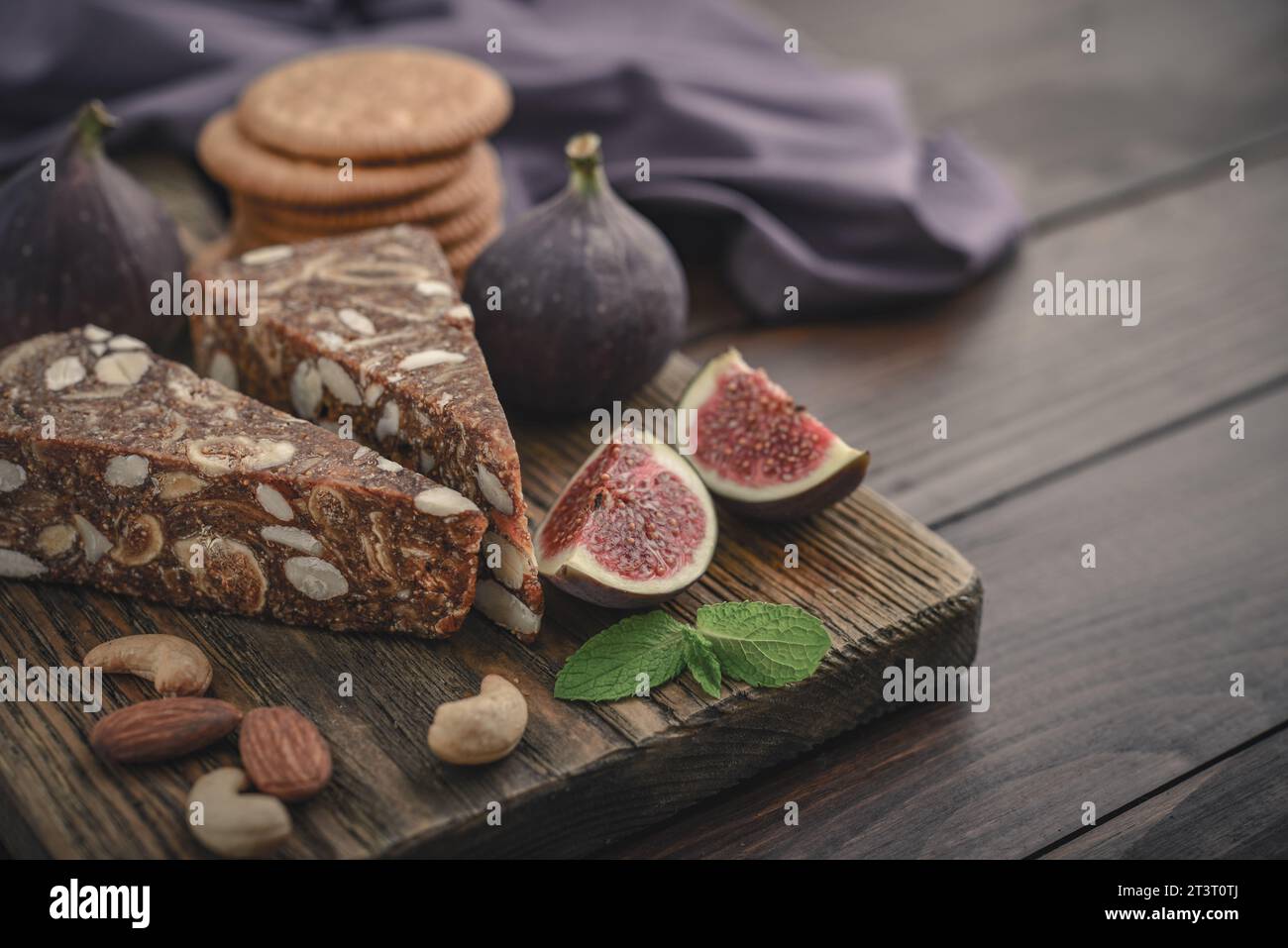 Pan de Higo: Spanisches Feigenbrot auf Holzschneidebrett mit frischen Feigen und Mandeln aus der Nähe Stockfoto