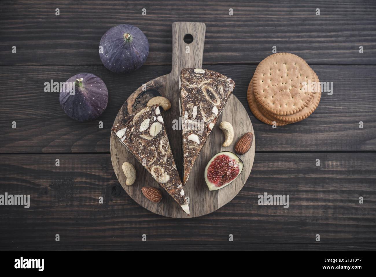 Pan de Higo – spanisches Feigenbrot auf einem Holzschneidebrett mit frischen Feigen und Mandeln von oben Stockfoto