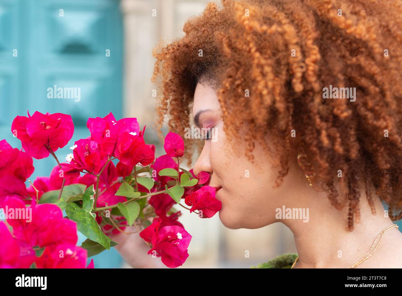 Nahaufnahme des Gesichts einer rothaarigen Frau mit geschlossenen Augen, die eine Blume nahe an ihrer Nase riecht. Selbstbewusste und ruhige Person. Stockfoto