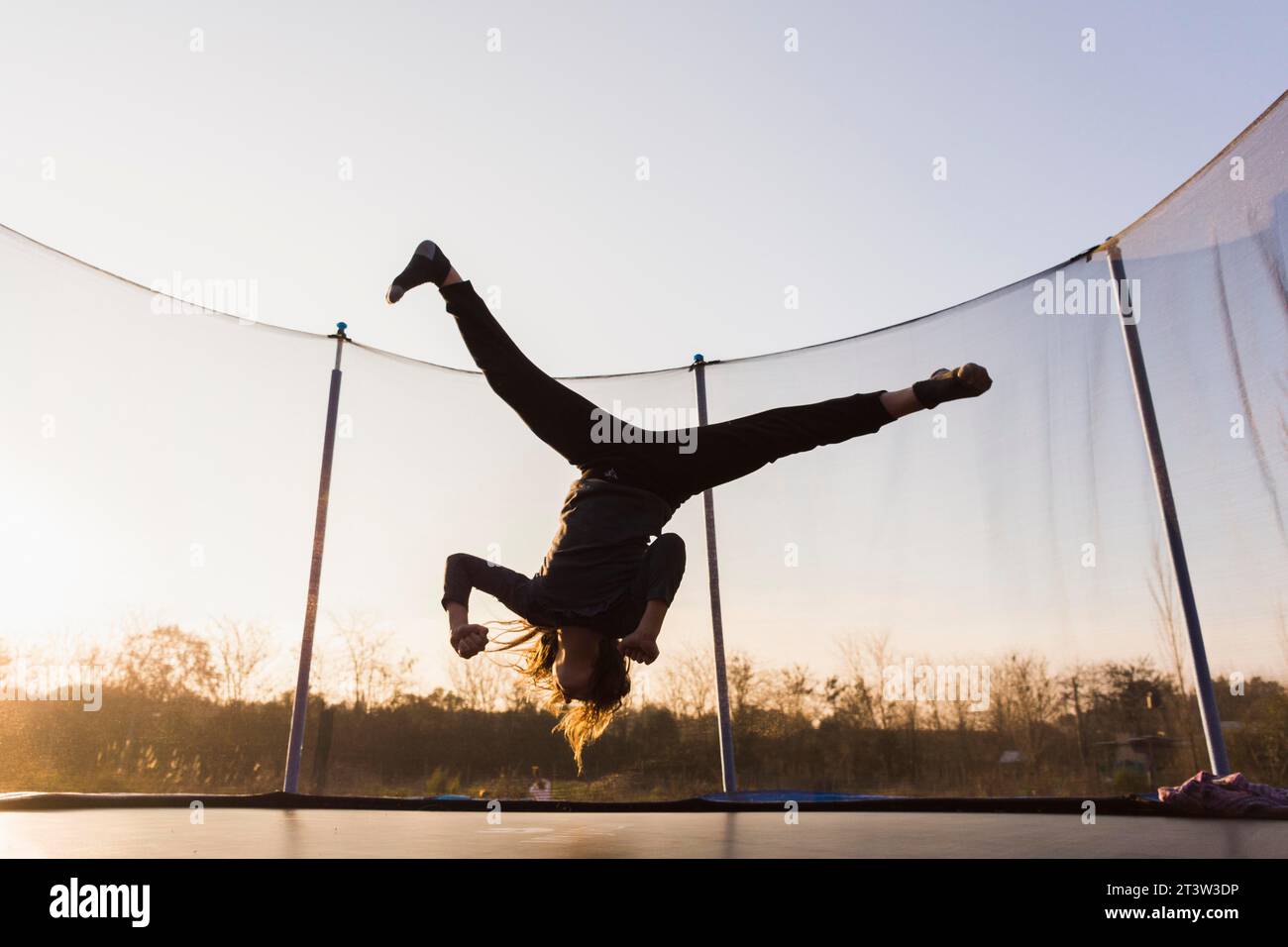 Silhouette-Mädchen, das Trampolin springt, spaltet sich Stockfoto