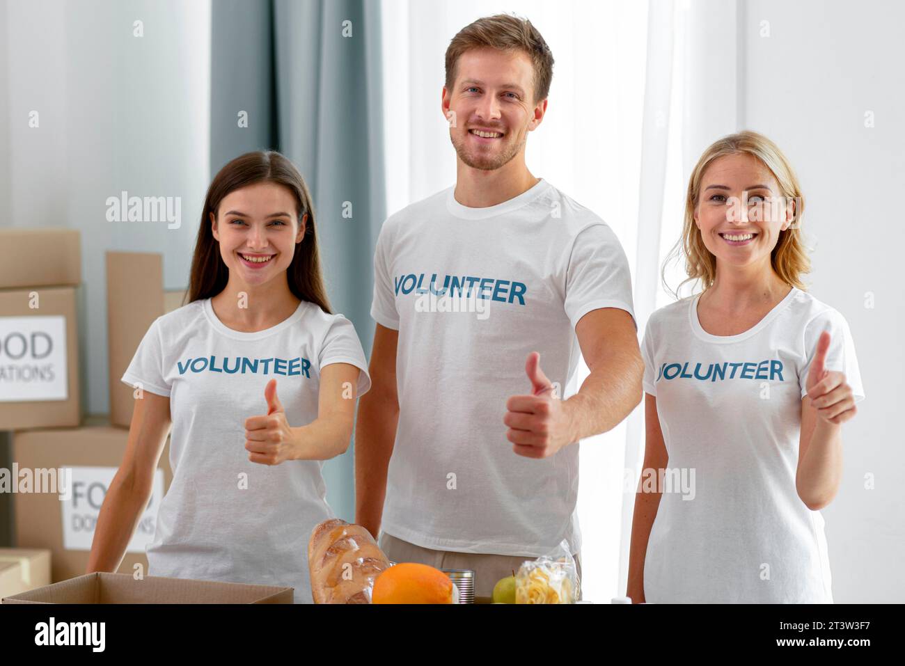 Smiley-Freiwillige posieren, während sie die Daumen hochgeben Stockfoto