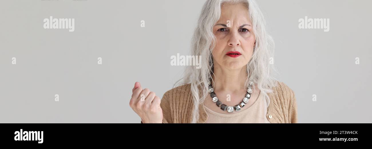 Eine besorgte ältere Frau mit langen, lockeren Haaren steht im Studio Stockfoto