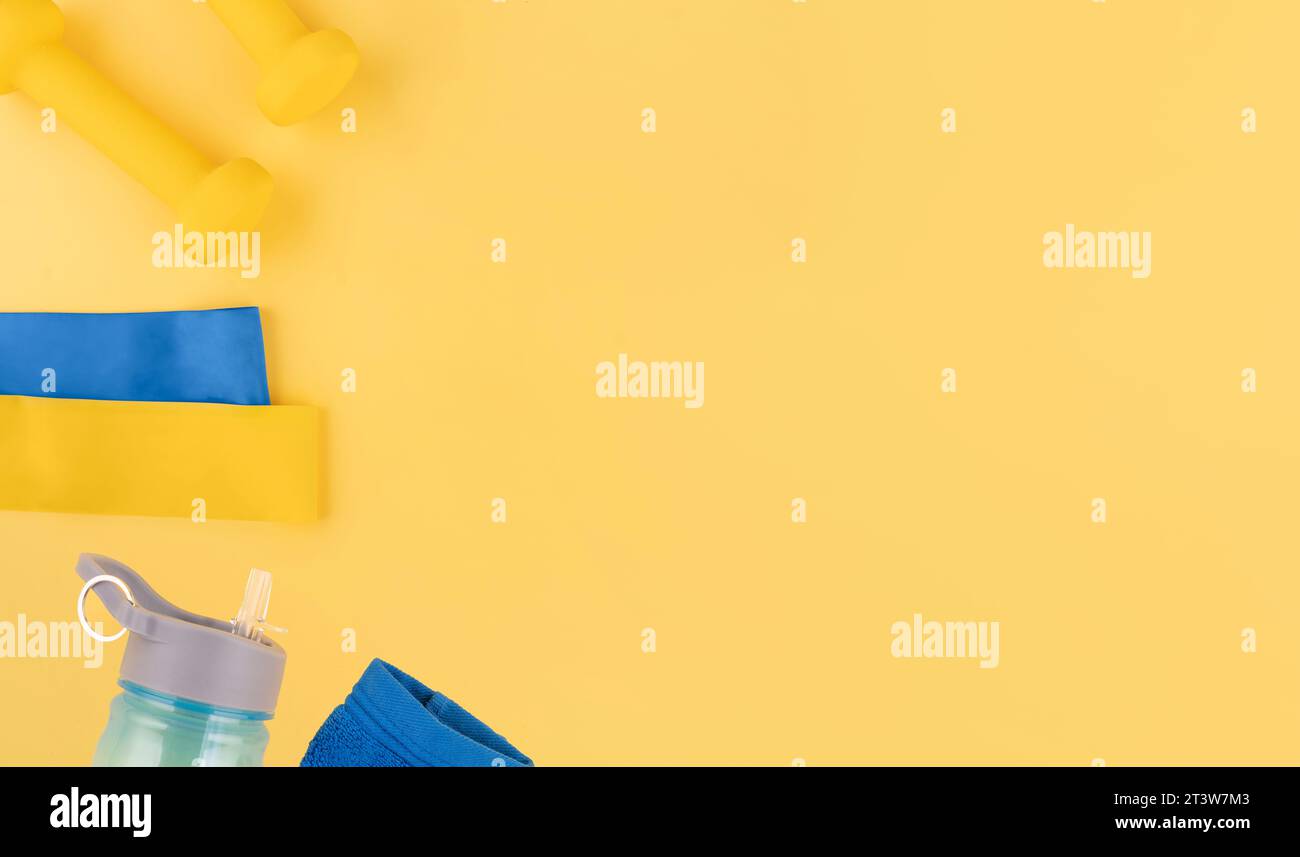Neopren-Kurzhanteln, Fitness-Bänder elastisch, Flasche, Handtuch auf gelbem Hintergrund Top View, Flat Lay Fitness und gesundes Leben, Wellness-Konzept. Stockfoto