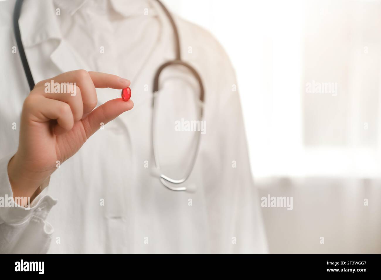 Ergänzungen für ein stärkeres Immunsystem. Nahaufnahme einer jungen Ärztin mit einer roten Einzelpille, einer Krankenschwester mit weißem Mantel und Stethoskop. Mittel Stockfoto