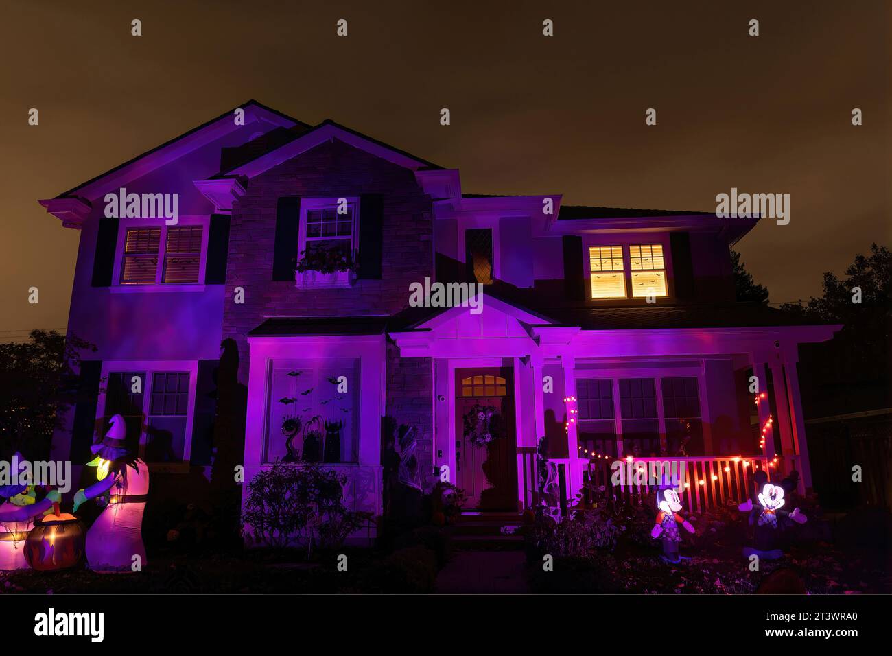 Rosa und lila beleuchtetes Halloween-Haus mit hellem Nachthimmel Stockfoto