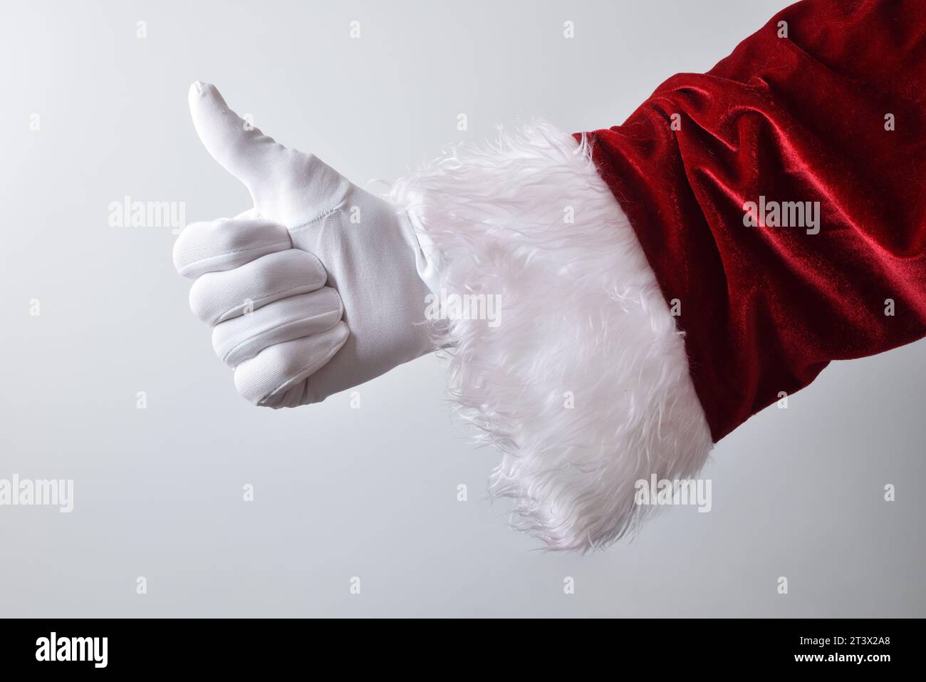 weihnachtsmann Hand mit weißem Handschuh und roter traditioneller Tracht, die Geste macht, etwas mit weißem Hintergrund zu fangen. Stockfoto