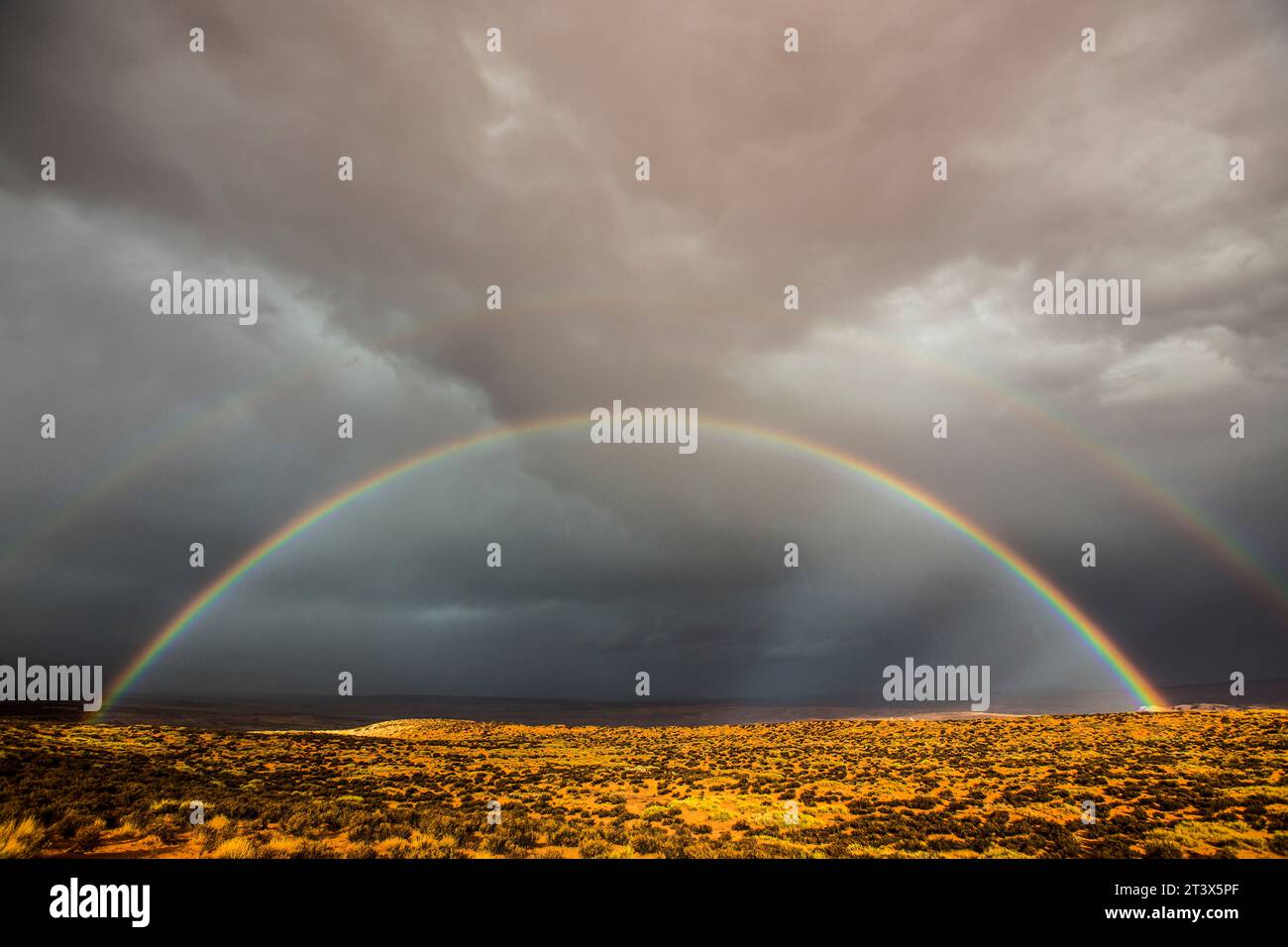 Ein doppelter Regenbogen glänzt über einer Wüstenlandschaft. Stockfoto