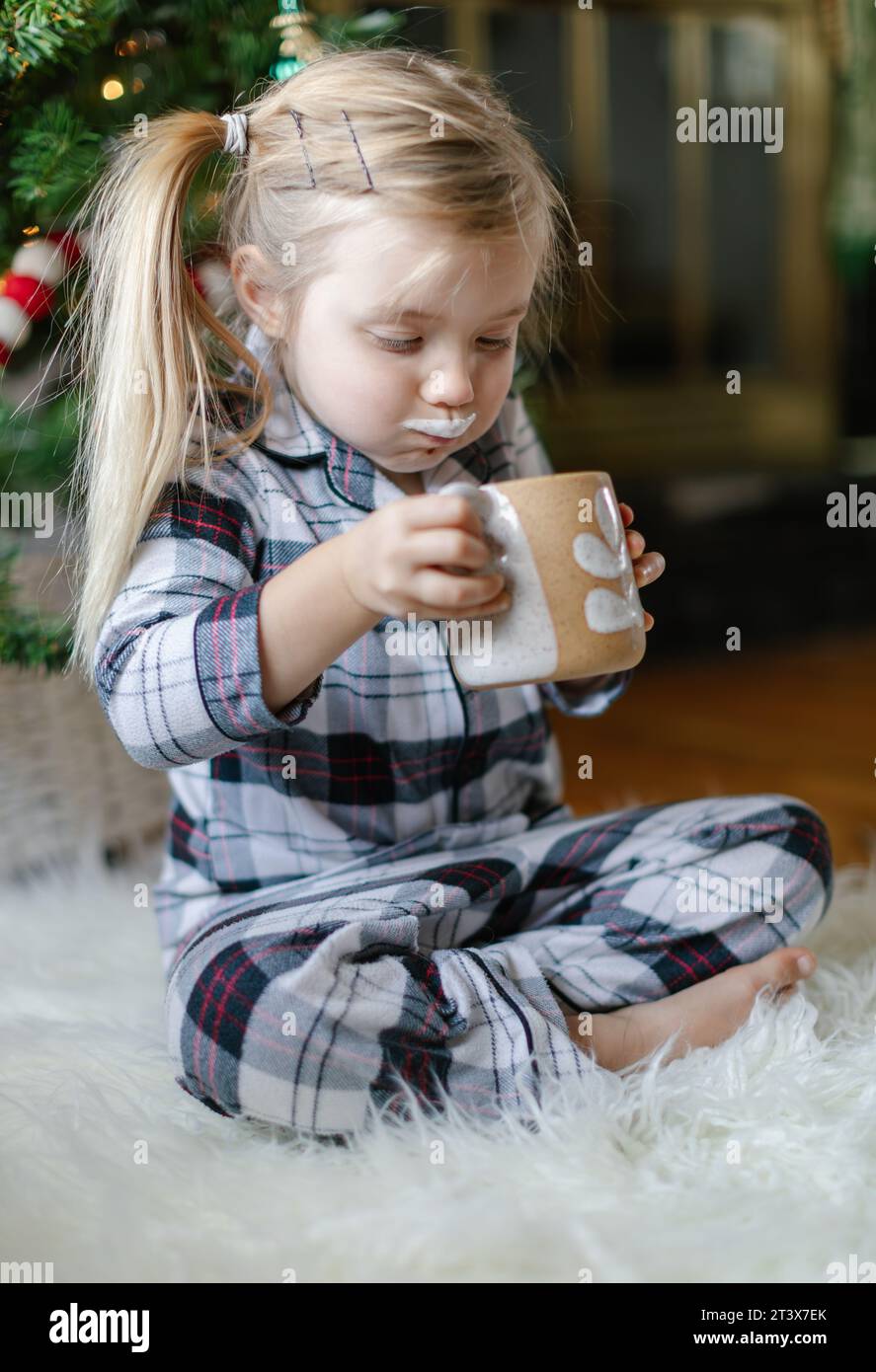Glückliches Kleinkind genießt Kakao, Wangen und Milchschnurrbart Stockfoto