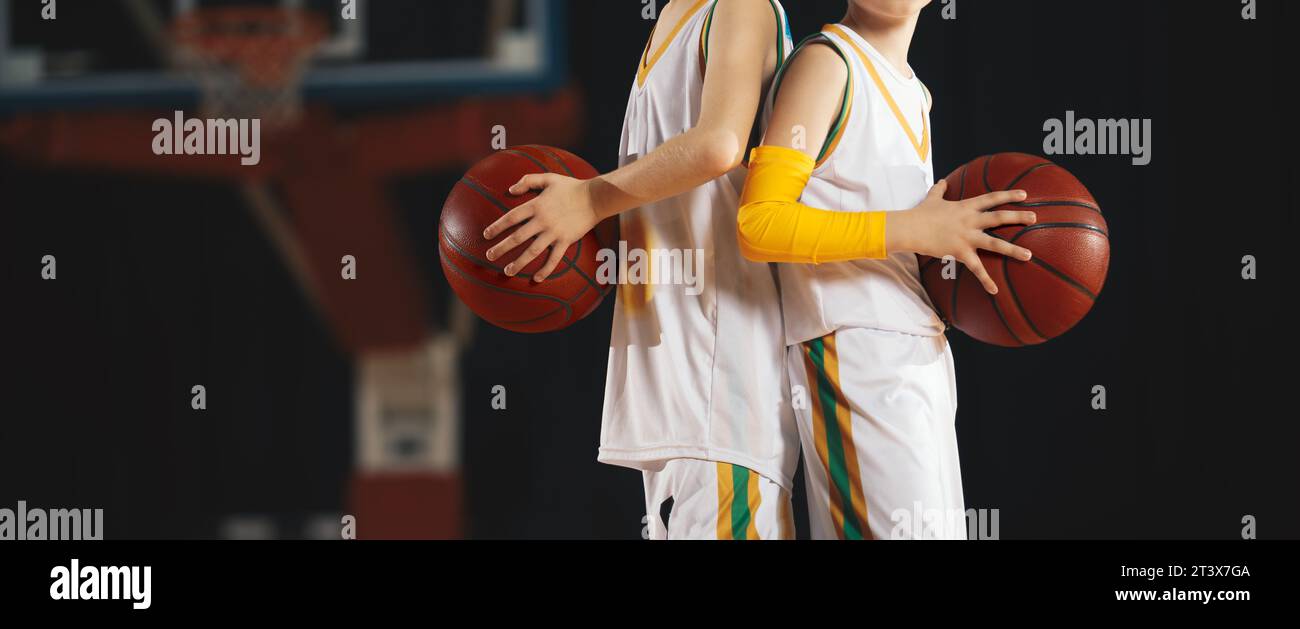 Basketballkurs für Kinder. Kinder beim Basketballtraining. Zwei Jugendspieler in Sportkleidung, die klassische orangene Basketbälle halten Stockfoto