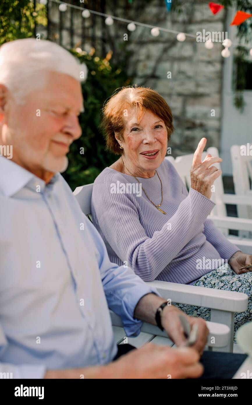 Porträt einer lächelnden Seniorin, die beim Mann im Hinterhof sitzt Stockfoto