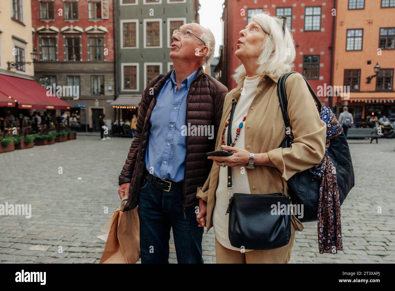 Überraschendes Seniorenpaar, das aufblickte, während er zusammen in der Stadt stand Stockfoto
