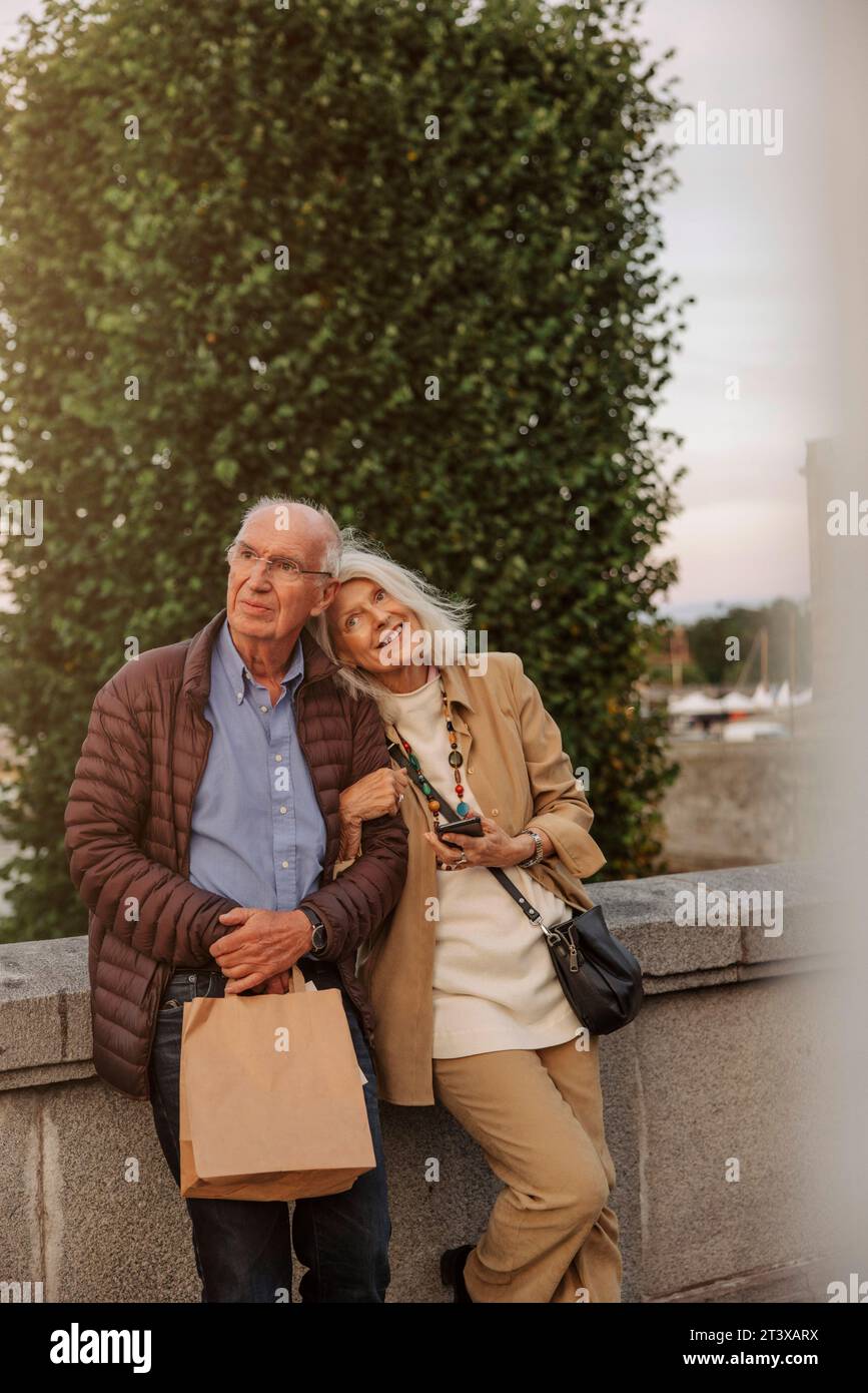 Ein nachdenkliches Seniorenpaar, das sich auf das Geländer stützt und wegblickt Stockfoto