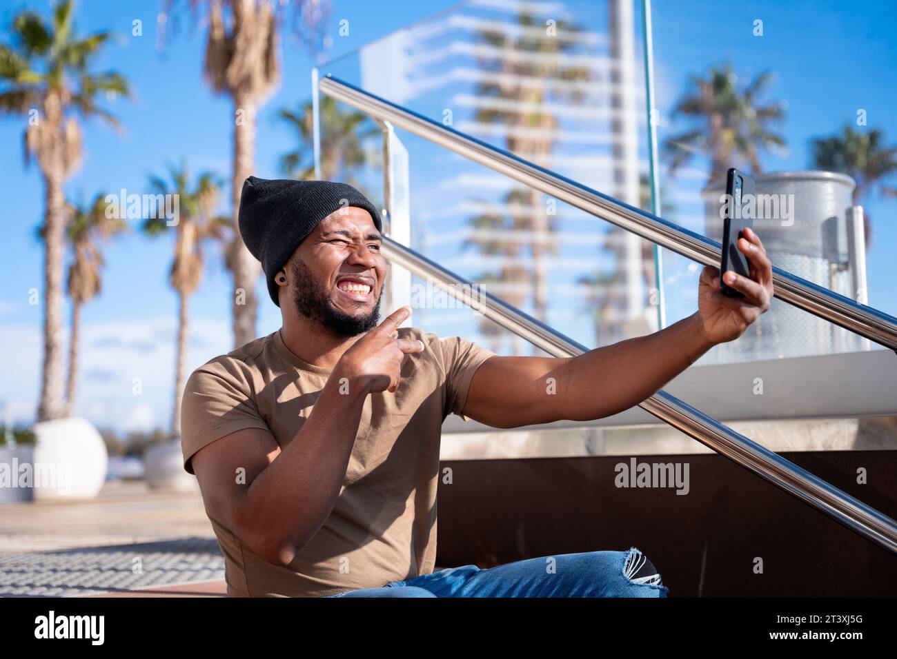 Glücklicher schwarzer Mann, der mit einem Smartphone ein Selbstfoto macht. Stockfoto