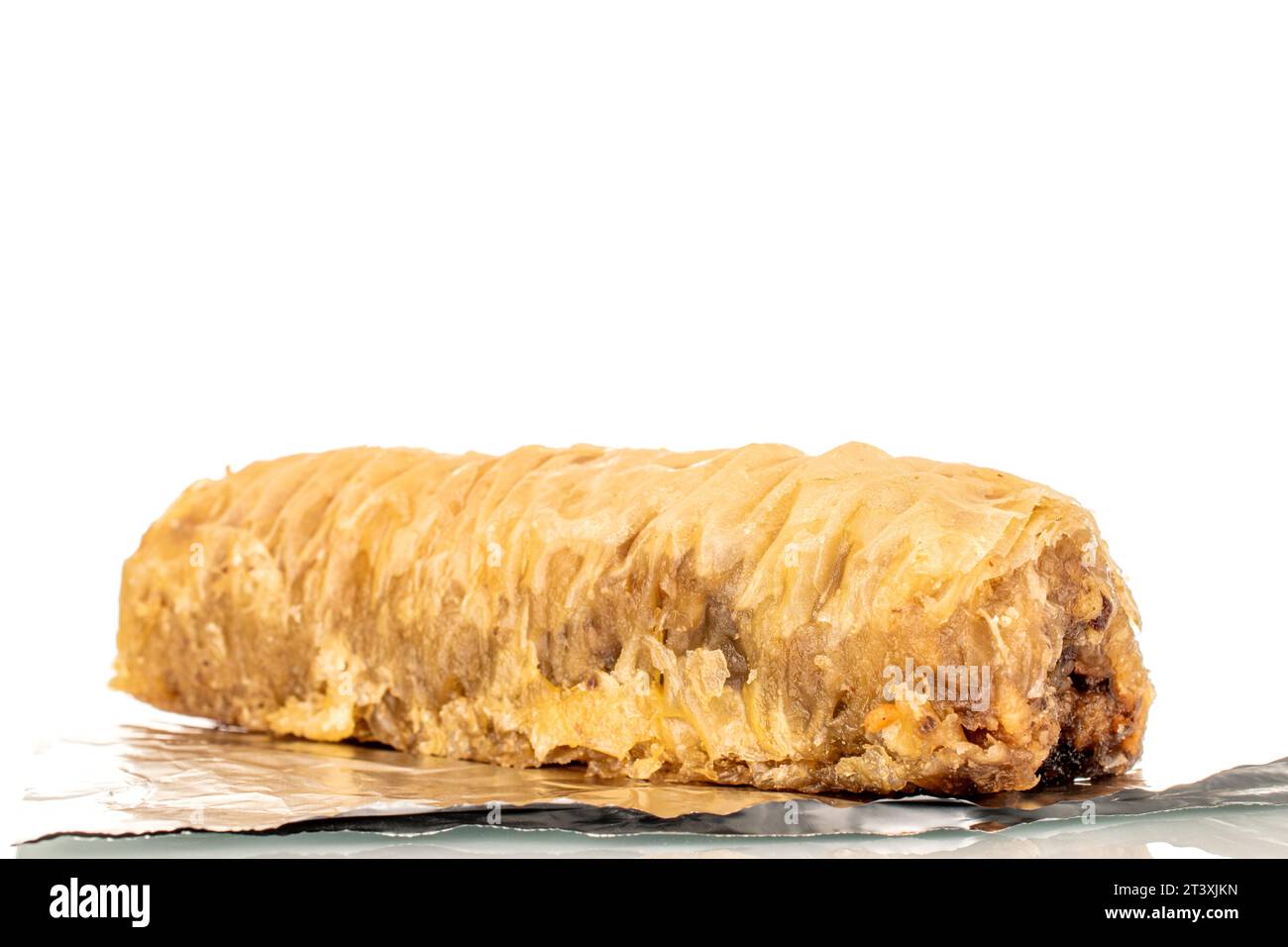 Ein Stück süßer Baklava auf Folie, Makro, isoliert auf weißem Hintergrund. Stockfoto