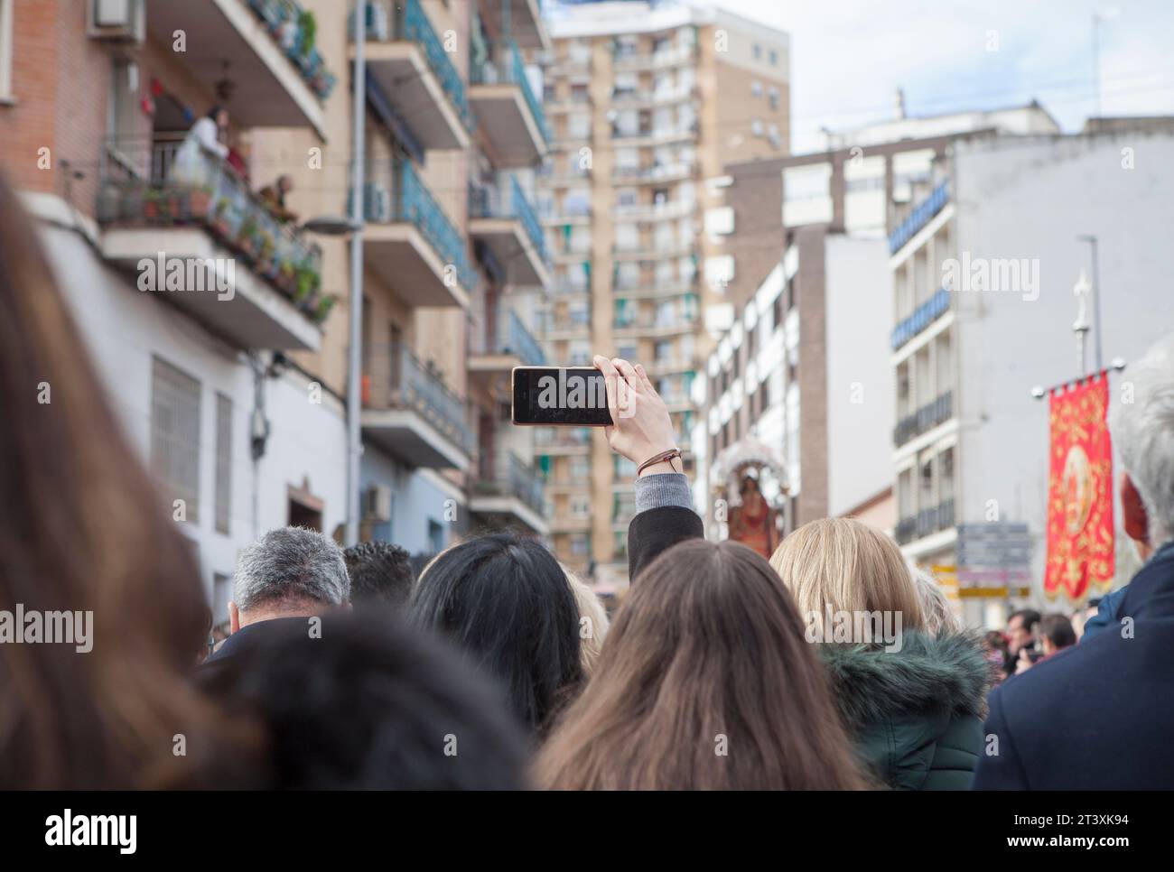 Merida, Spanien - 10. Dezember 2022: Eine Frau hebt den Arm, um mit ihrem Smartphone die Eulalia-Prozession von Merida aufzunehmen. Märtyrer verehrt mit großem Entwickler Stockfoto