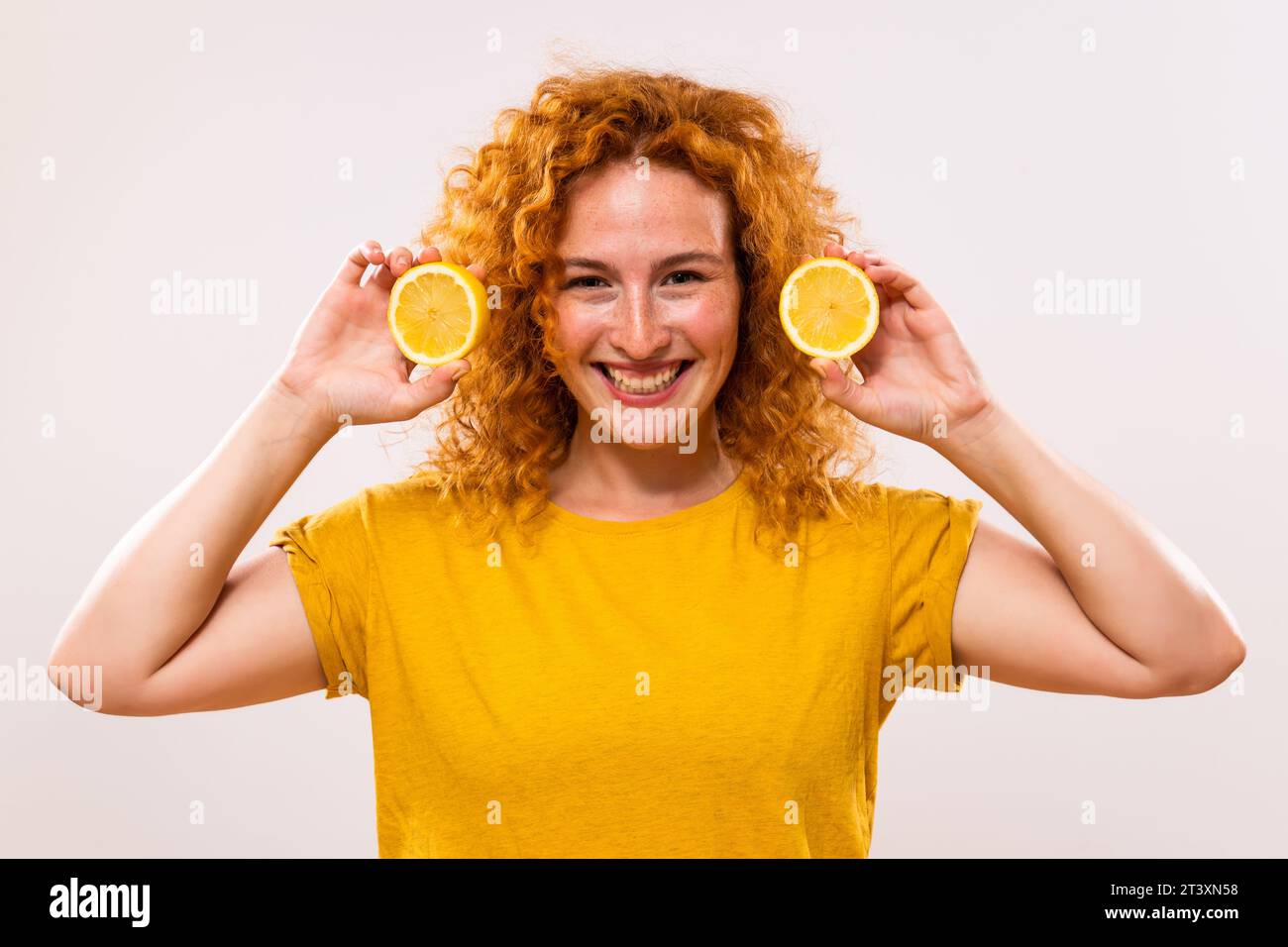Die schöne Ingwerfrau hält Zitronenscheiben in der Hand. Stockfoto