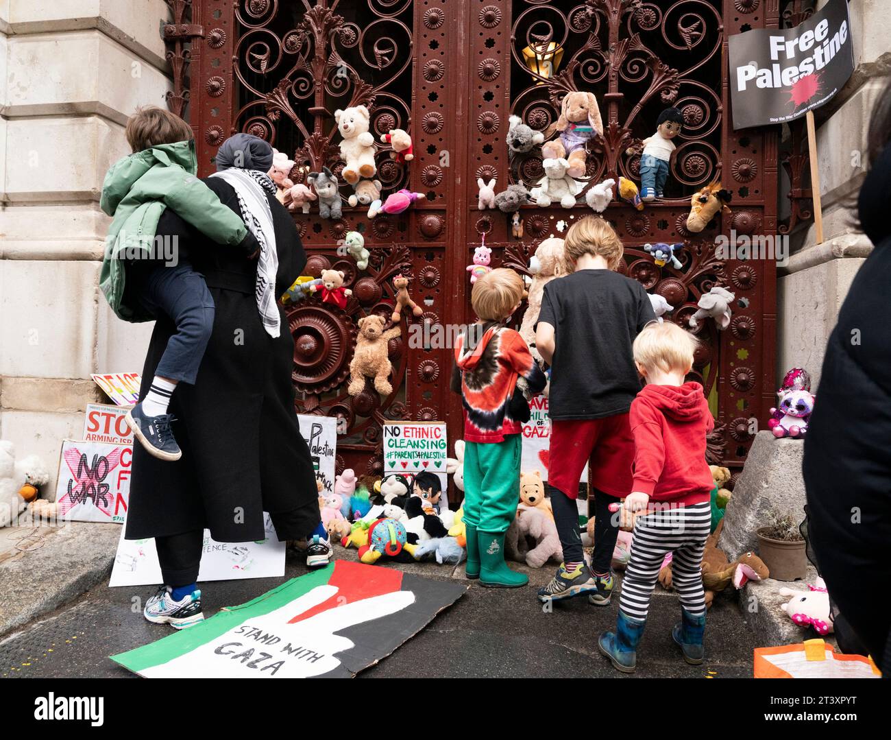 Eltern und Kinder legen kuschelige Spielzeuge über den Eingang des Außenministeriums in London, während sie protestieren, um das Leben von Kindern in Gaza zu retten. Jedes Spielzeug stellt ein palästinensisches Kind dar, das während des israelisch-Hamas-Konflikts getötet wurde. Bilddatum: Freitag, 27. Oktober 2023. Stockfoto