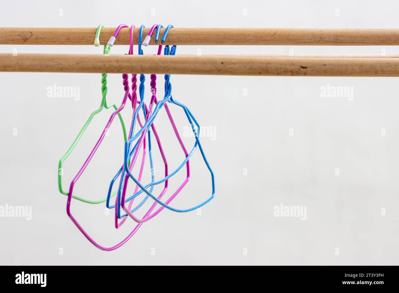 Kunststoffbügel hängen an einer Holzstange Stockfoto
