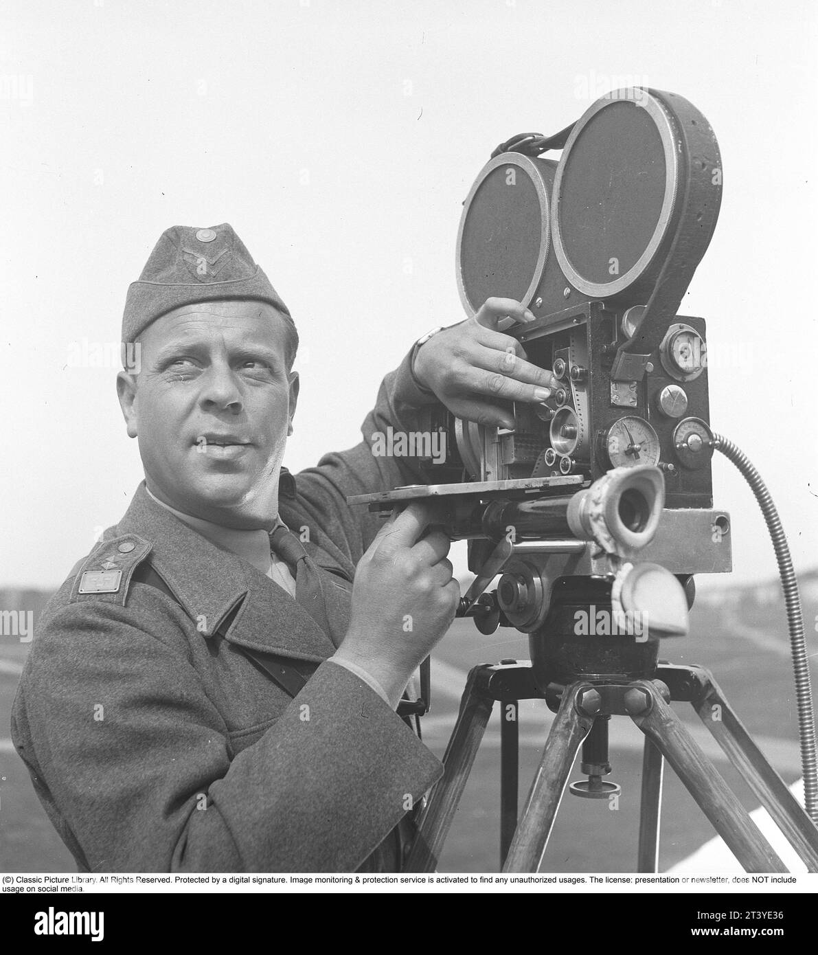 Dreharbeiten in den 1940er Jahren Ein Militärfilm wird produziert und der Kameramann montiert die Filmrolle in die Kamera. Er hat eine schwedische Armeeuniform und Schweden 1943 Ref. E31-3 Stockfoto