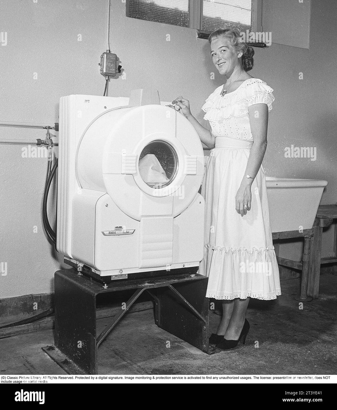 In den 1950er Jahren Eine junge Frau an einer modernen amerikanischen Waschmaschine des Herstellers Bendix. Das Modell war die erste automatische Waschmaschine und ähnelte nicht den heutigen Waschmaschinen. Schweden 1950. Kristoffersson Ref. AZ78-8 Stockfoto