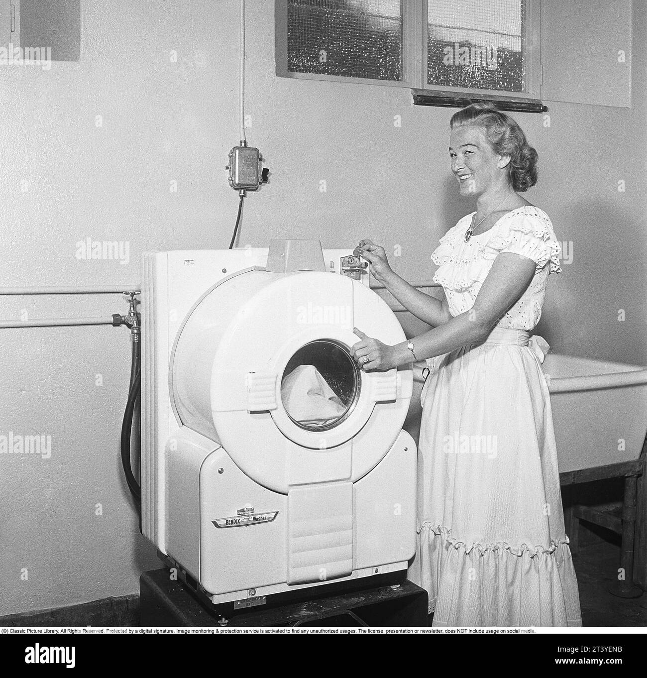 In den 1950er Jahren Eine junge Frau an einer modernen amerikanischen Waschmaschine des Herstellers Bendix. Das Modell war die erste automatische Waschmaschine und ähnelte nicht den heutigen Waschmaschinen. Schweden 1950. Kristoffersson Ref. AZ78-7 Stockfoto