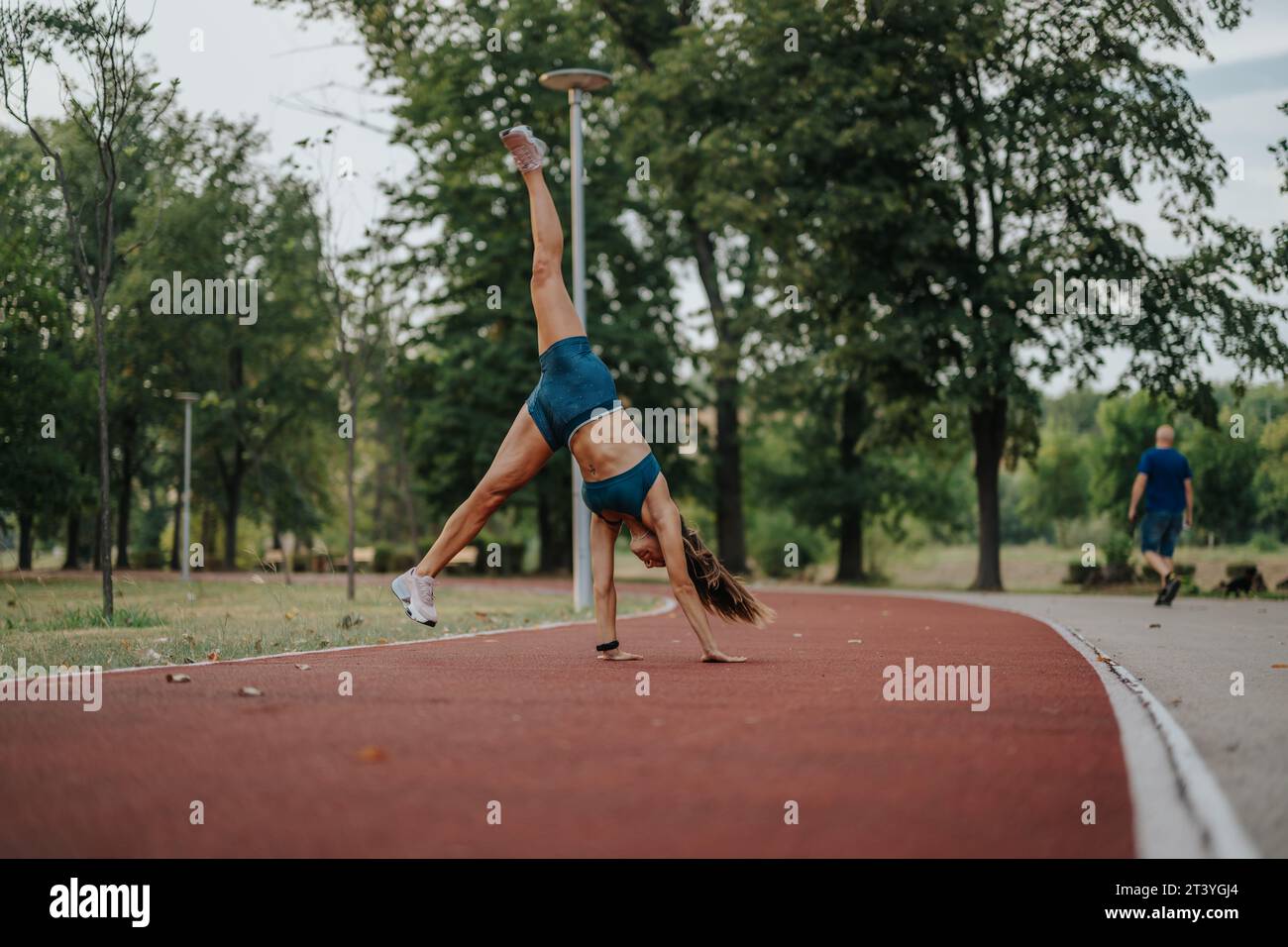 FIT Girl in einem grünen Park führt beeindruckende 360-Grad-Laufräder und -Flips aus und zeigt ihre Sportlichkeit, Flexibilität und Stärke. Stockfoto