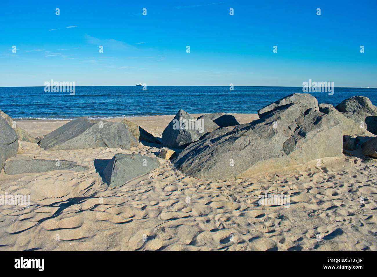 Kleine Wellen stürzen an einem sonnigen Herbsttag an einem Sandy Hook, New Jersey, in ein felsiges Ufer Stockfoto