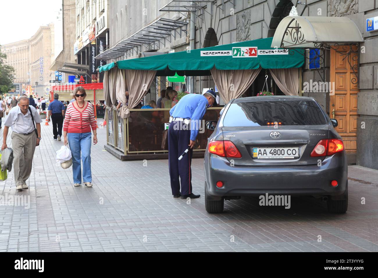 Der Polizist inspiziert den Fahrer von Toyota auf dem Fußgängerweg in Kiew, Ukraine, als gewöhnliche Ukrainer vorbeifahren, weil sie den Fahrer fürchten Stockfoto