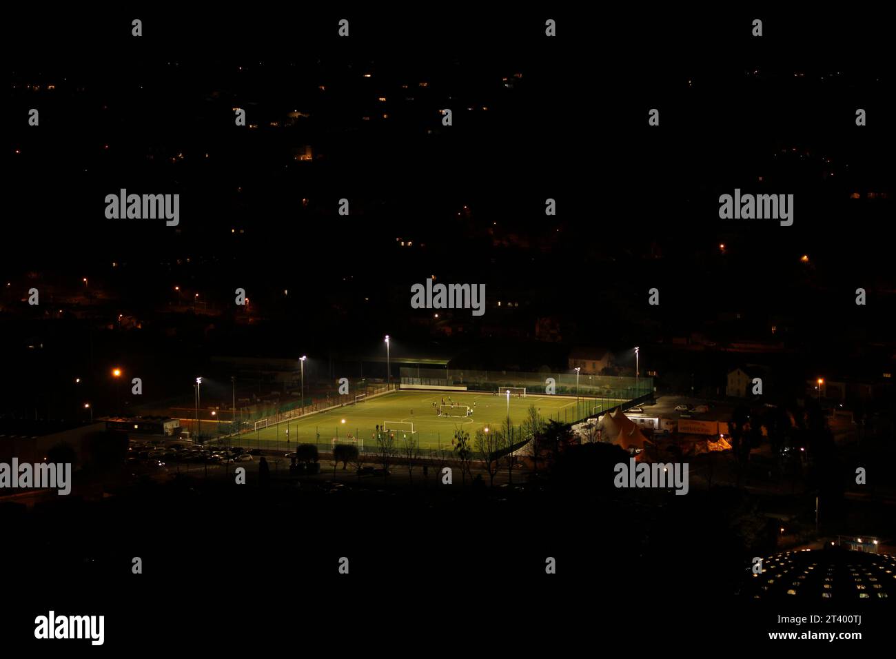 Fußballplatz oder Fußballplatz bei Nacht, von künstlichen Lampen umgeben, umgeben von dunklen Hängen. Konzept für Sport in der Nacht, Spiel durch alles Stockfoto