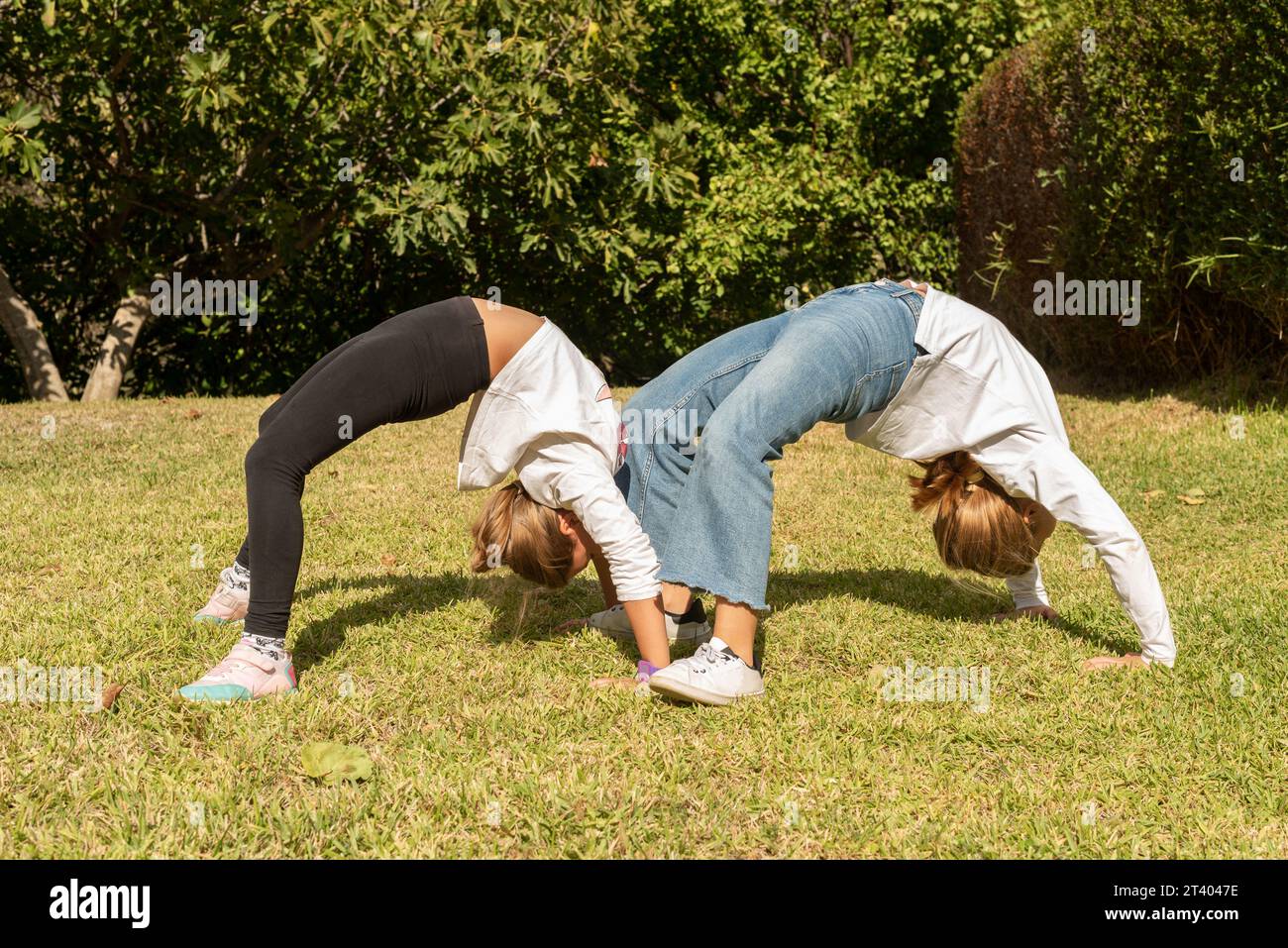 Zwei Mädchen im Park machen akrobatische Übungen. Kinder, die im Freien spielen und an Gymnastikaktivitäten teilnehmen. Gesundes Leben und gesunde Ernährung im Out Stockfoto