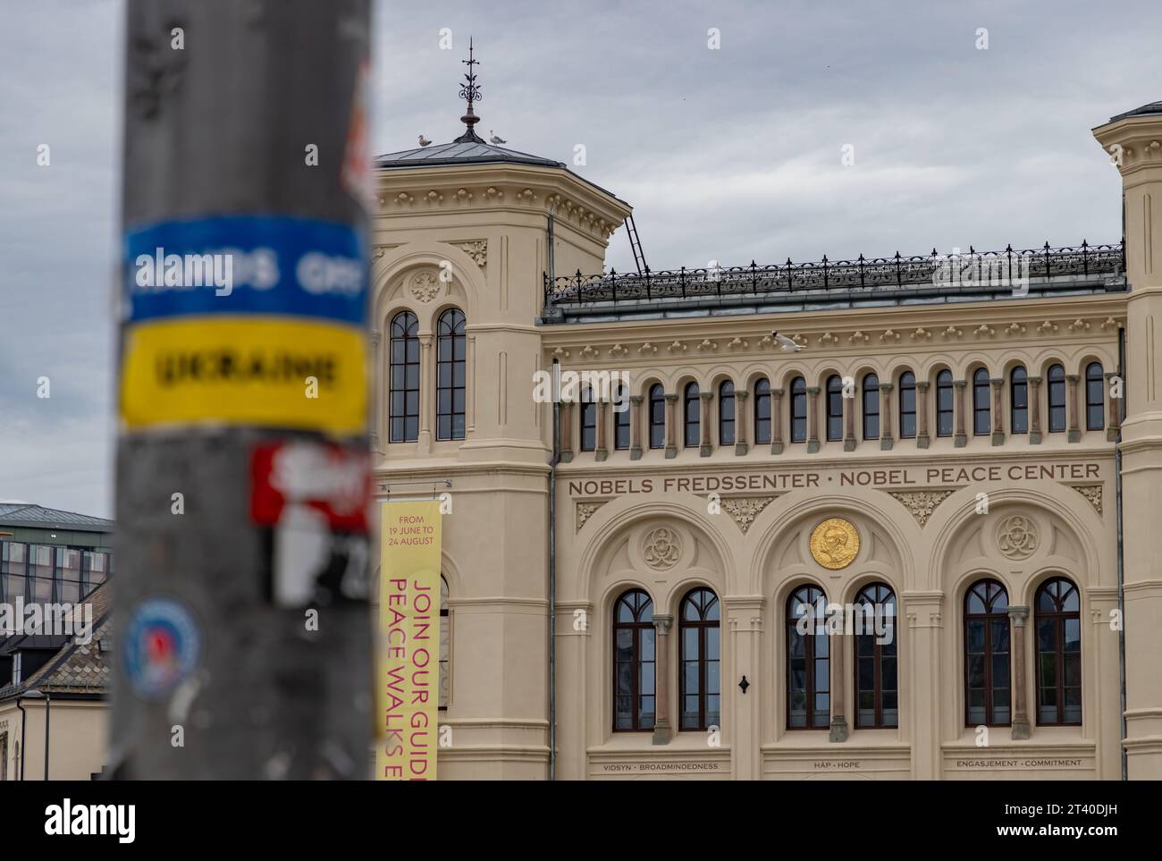 Ein Bild des Friedensnobelzentrums und ein verschwommener Aufkleber Hände weg von der Ukraine im Vordergrund. Stockfoto