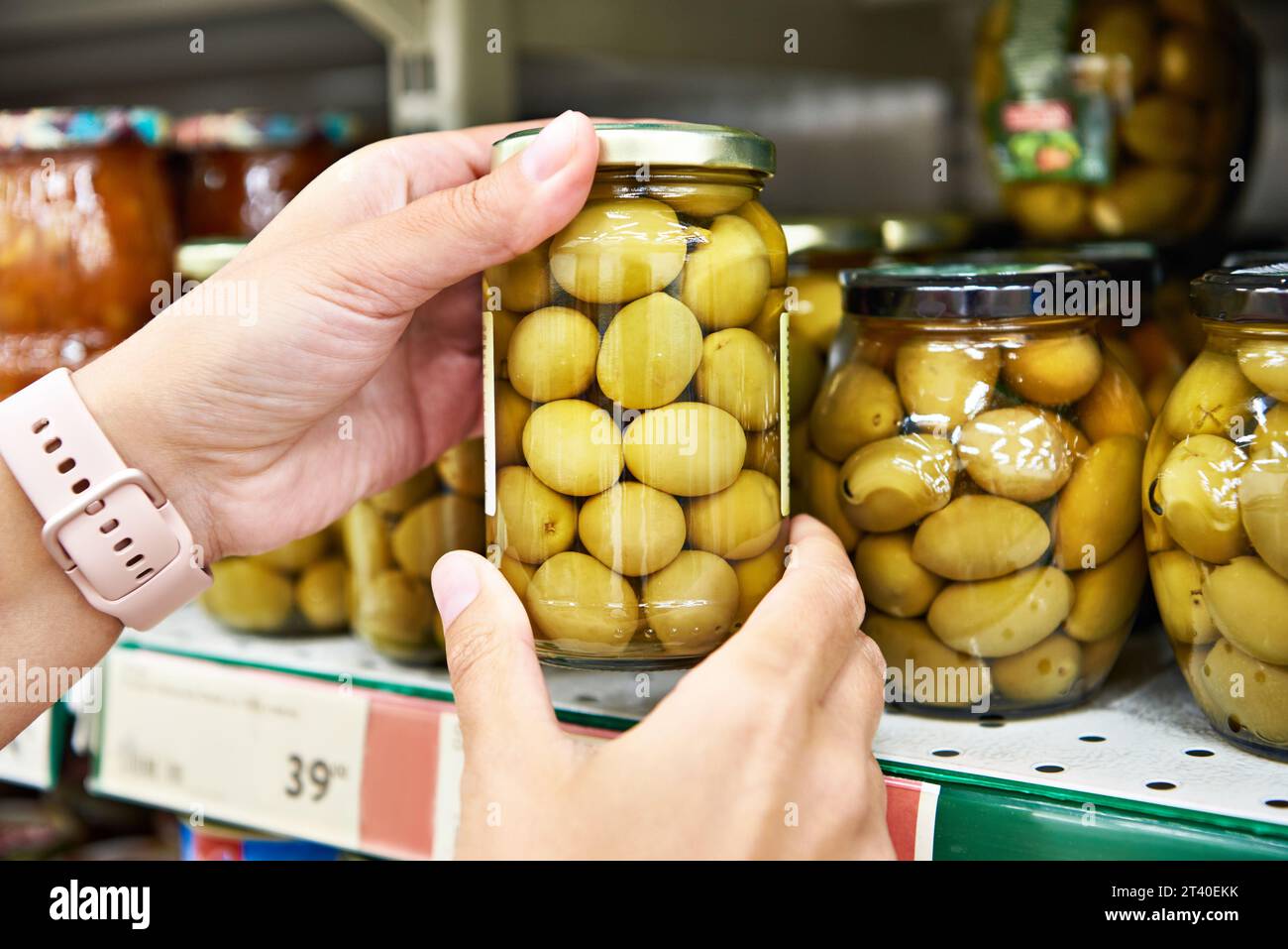 Oliven in Dosen in den Händen eines Käufers in einem Geschäft Stockfoto
