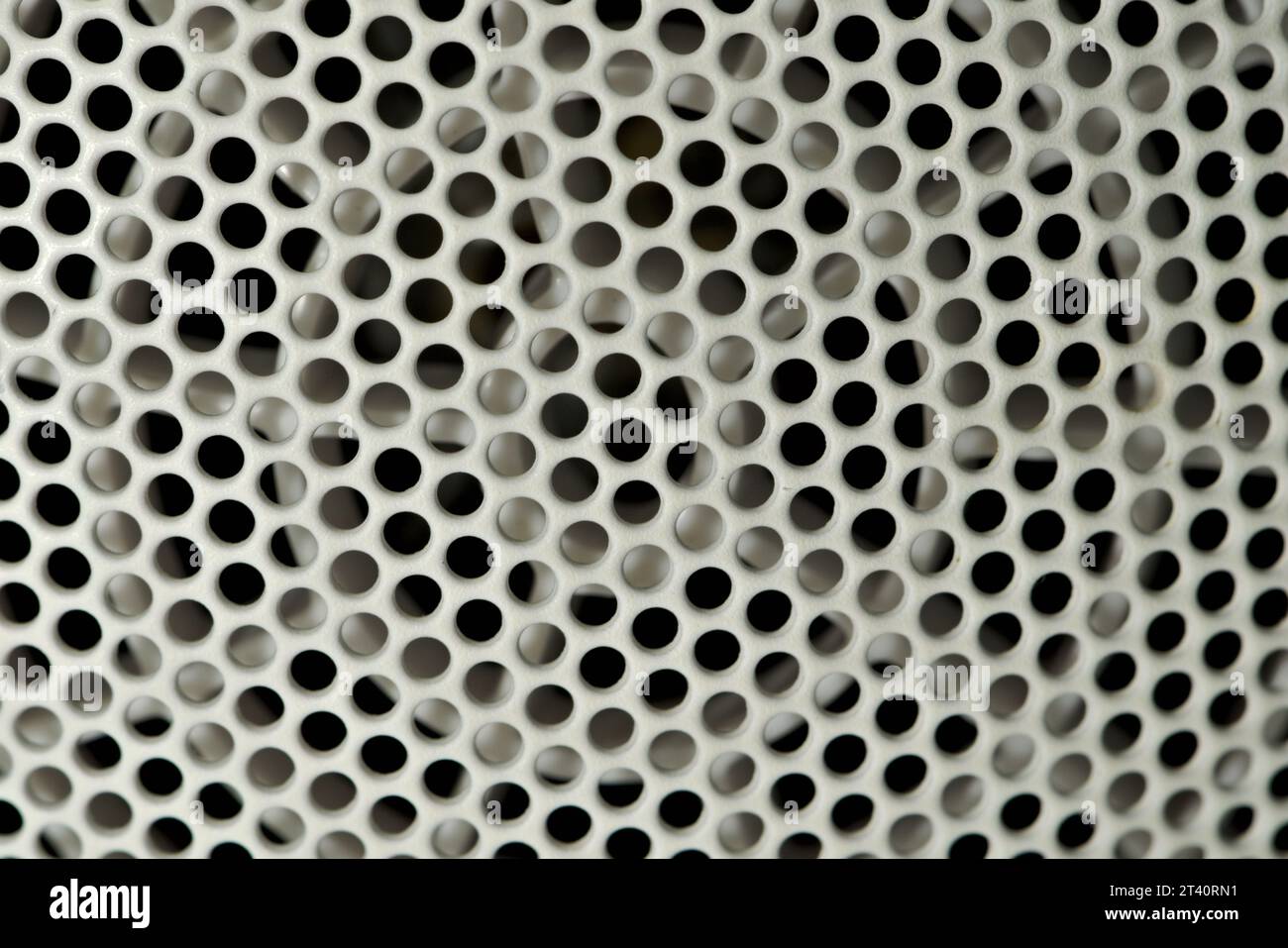 Geometrisches Muster der Löcher am Metallgitter. Abstrakte Detailfotografie der Perforation an der Rückseite des Föhns. Stockfoto
