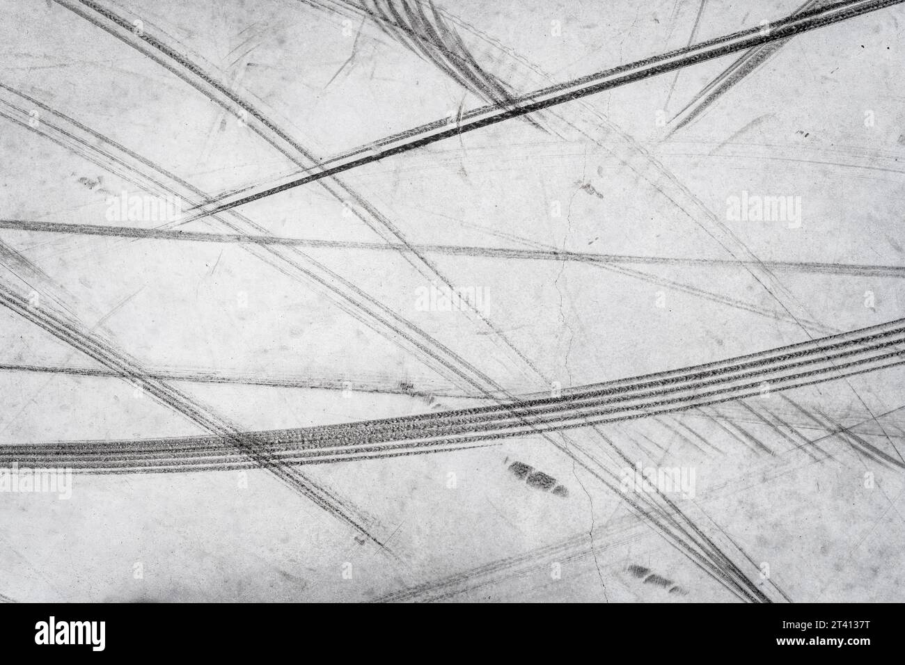 Strukturierter Hintergrund von Fahrzeugspuren auf der Straße von Rollern, Fahrrädern, Fahrradweel. Reifenaufdruck Textur des Transports Stockfoto