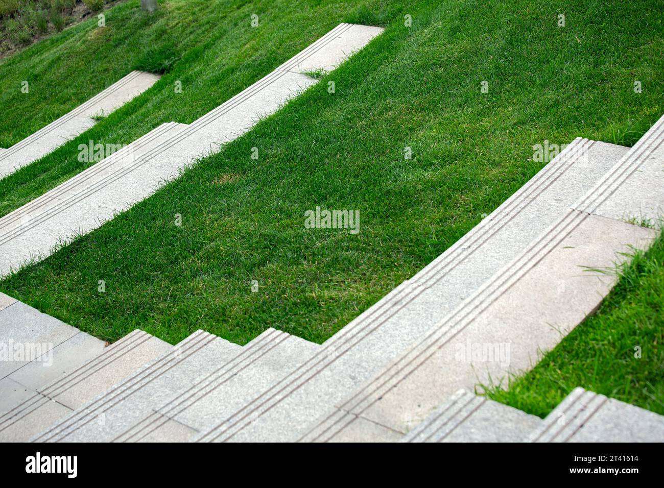 Treppen mit Granitstufen in der Nähe des Rasenplatzes auf dem Hügel im Sommerpark, niemand. Stockfoto